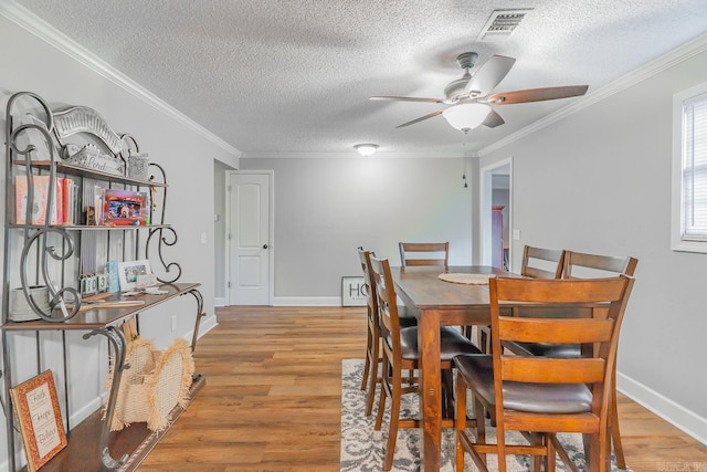 dining space with a textured ceiling, light hardwood / wood-style floors, ceiling fan, and crown molding