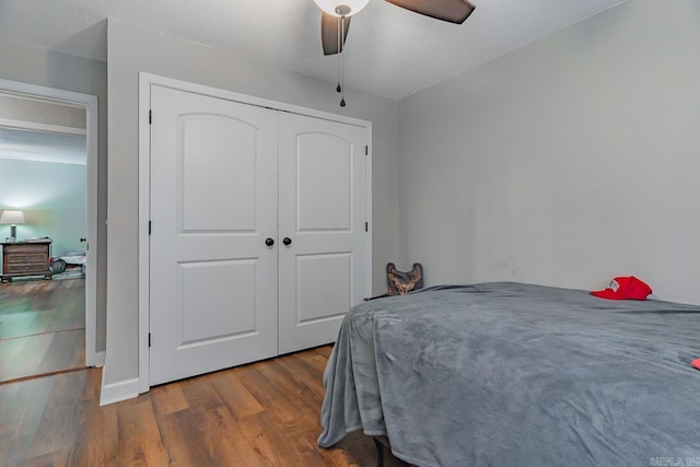 bedroom with dark hardwood / wood-style flooring, a closet, and ceiling fan