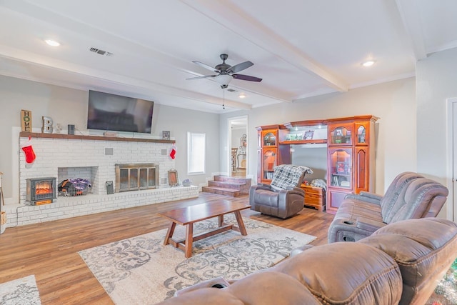 living room with beam ceiling, ceiling fan, light hardwood / wood-style floors, a fireplace, and ornamental molding