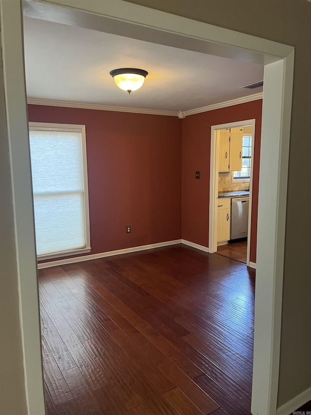 spare room featuring crown molding, plenty of natural light, and dark wood-type flooring