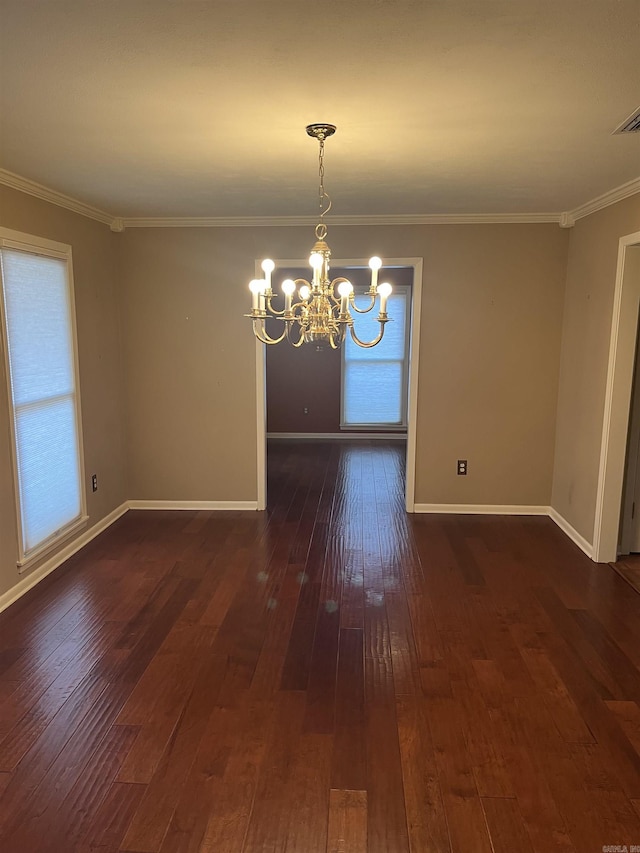 empty room featuring dark hardwood / wood-style flooring, crown molding, and a chandelier