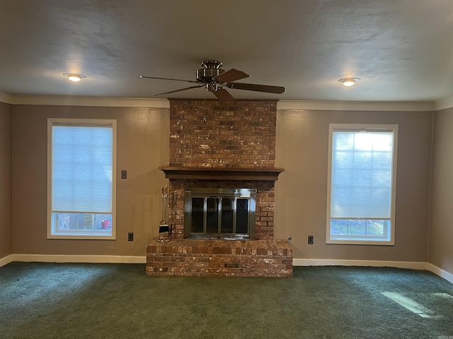 unfurnished living room with dark colored carpet, ceiling fan, ornamental molding, and a brick fireplace