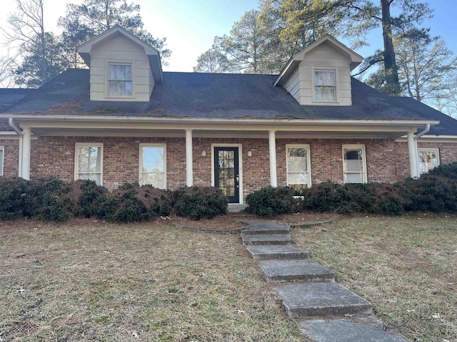 new england style home featuring covered porch and a front yard