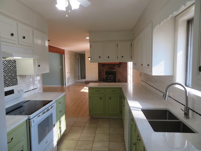 kitchen with tasteful backsplash, sink, green cabinets, white electric range oven, and light tile patterned floors