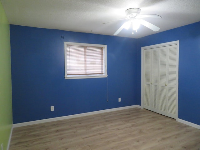 unfurnished bedroom featuring ceiling fan, a textured ceiling, a closet, and light hardwood / wood-style flooring