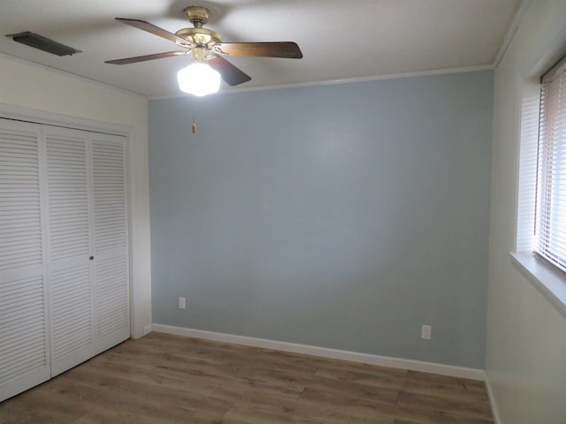 unfurnished bedroom featuring crown molding, ceiling fan, hardwood / wood-style floors, and a closet