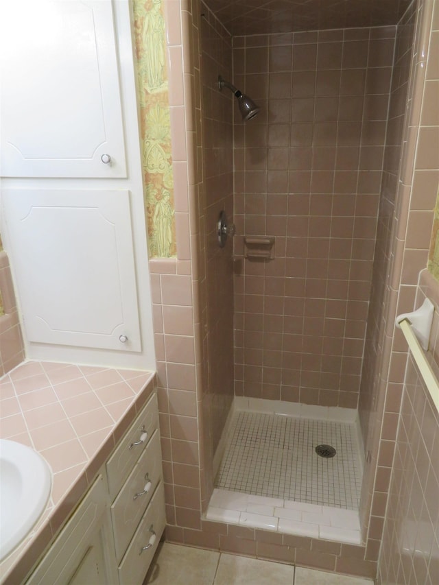 bathroom featuring vanity, tile patterned flooring, and tiled shower