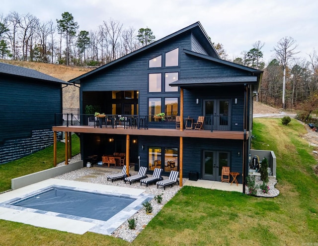 rear view of house featuring a lawn, a patio area, french doors, and a pool side deck