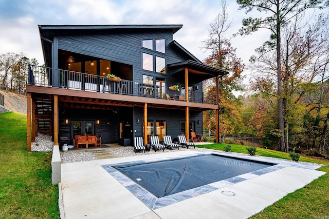 rear view of house with a patio area, a yard, french doors, and a covered pool