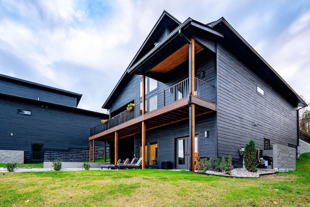 rear view of house featuring a balcony and a lawn