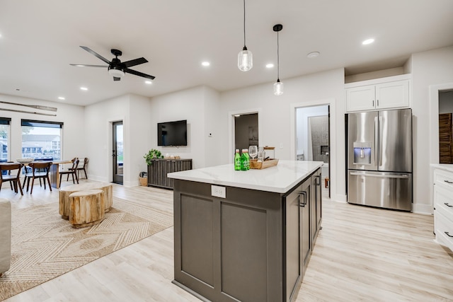 kitchen with white cabinetry, ceiling fan, stainless steel fridge, decorative light fixtures, and light wood-type flooring