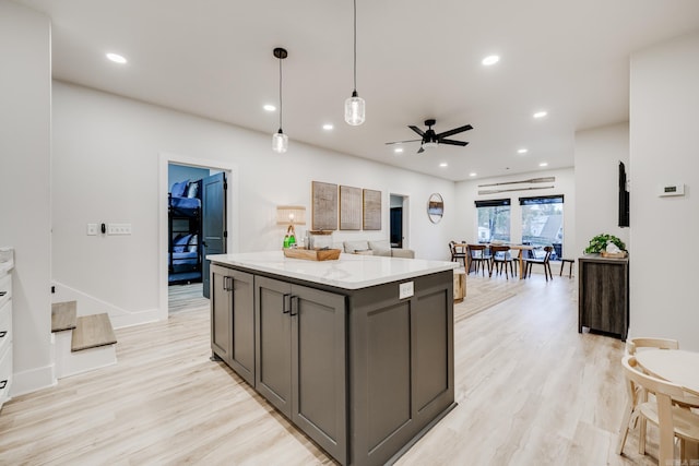 kitchen featuring gray cabinetry, a center island, ceiling fan, light wood-type flooring, and decorative light fixtures