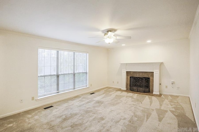 unfurnished living room featuring ceiling fan, a fireplace, crown molding, and light carpet