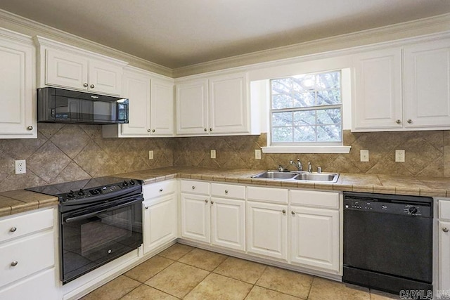 kitchen with black appliances, white cabinetry, sink, and tile countertops