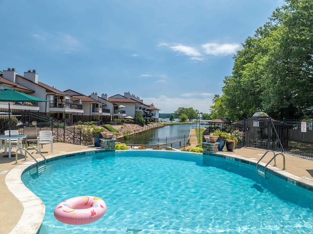 view of swimming pool featuring a water view and a patio