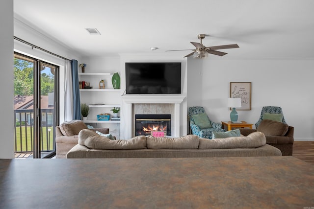 living room with a fireplace, built in shelves, ceiling fan, and wood-type flooring