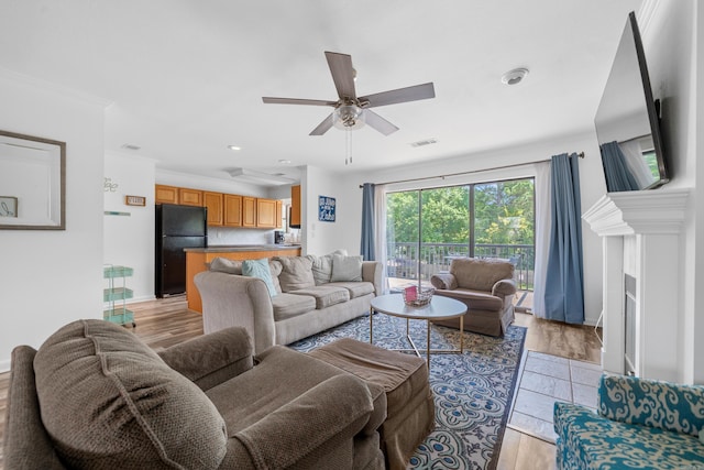 living room featuring light hardwood / wood-style flooring, ceiling fan, and crown molding