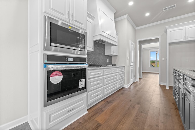 kitchen with decorative backsplash, appliances with stainless steel finishes, light stone counters, crown molding, and white cabinetry