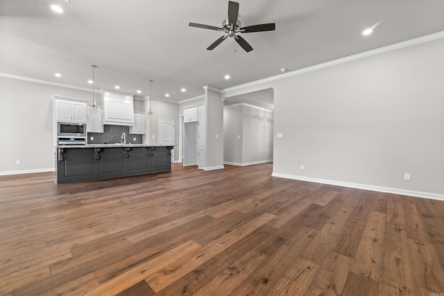 unfurnished living room with dark hardwood / wood-style flooring, ornamental molding, and sink