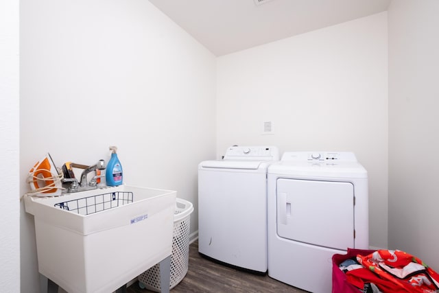 clothes washing area with dark hardwood / wood-style flooring, washer and clothes dryer, and sink