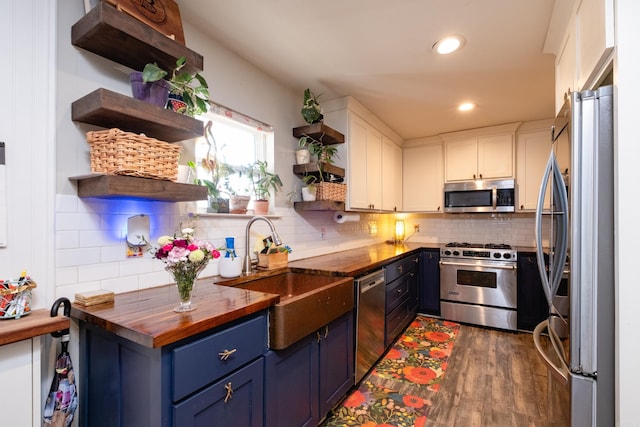 kitchen with wooden counters, blue cabinets, sink, white cabinetry, and stainless steel appliances