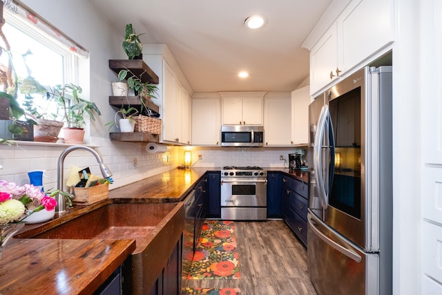 kitchen featuring wood counters, backsplash, dark wood-type flooring, white cabinetry, and stainless steel appliances