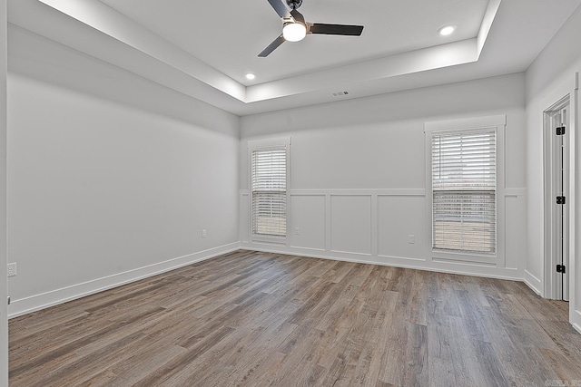 empty room featuring a tray ceiling, light hardwood / wood-style flooring, and ceiling fan