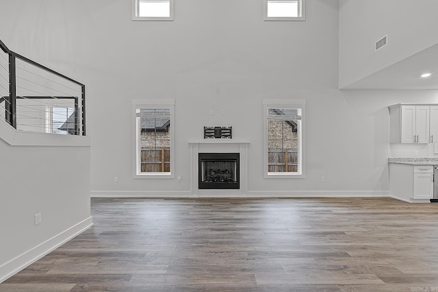 unfurnished living room with a high ceiling and light wood-type flooring