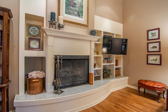 living room featuring a tile fireplace and light wood-type flooring