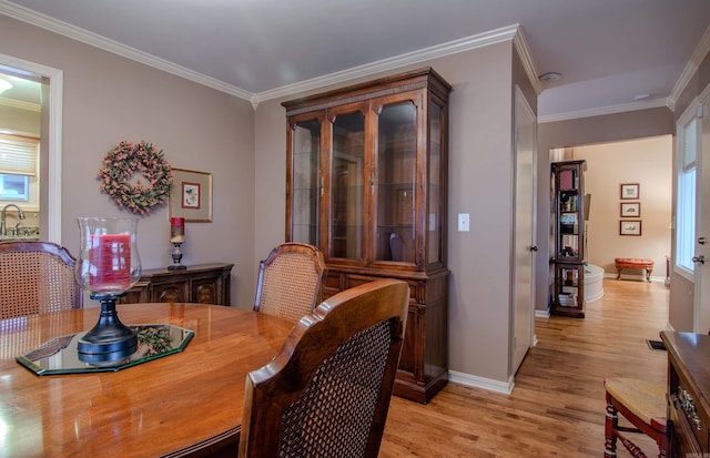 dining room with sink, light hardwood / wood-style floors, and ornamental molding