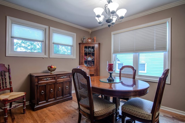 dining area with light hardwood / wood-style flooring, ornamental molding, and an inviting chandelier