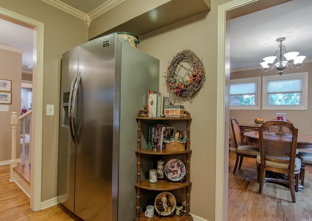 kitchen featuring stainless steel refrigerator with ice dispenser, ornamental molding, decorative light fixtures, light hardwood / wood-style flooring, and an inviting chandelier