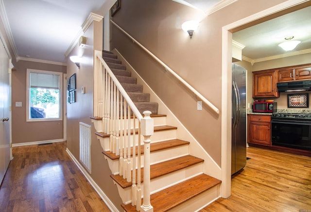 stairs with crown molding and hardwood / wood-style floors