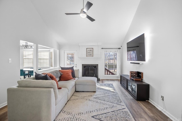 living room featuring ceiling fan with notable chandelier, a large fireplace, wood-type flooring, and a wealth of natural light