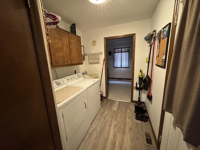 washroom featuring sink, cabinets, separate washer and dryer, light hardwood / wood-style floors, and a textured ceiling