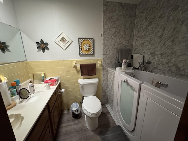 bathroom with vanity, hardwood / wood-style flooring, tile walls, washer / dryer, and toilet