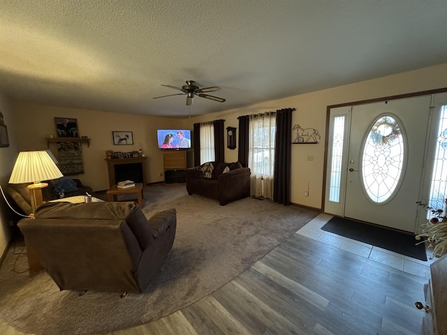 living room with ceiling fan, wood-type flooring, and a textured ceiling