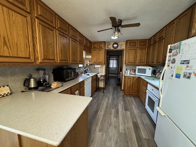 kitchen with ceiling fan, dark wood-type flooring, kitchen peninsula, a textured ceiling, and white appliances