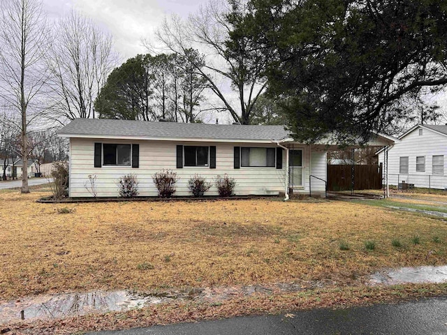 single story home featuring a carport, a front yard, and fence