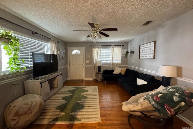 living room featuring visible vents, ceiling fan, a textured ceiling, and wood finished floors