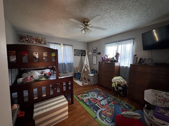 bedroom with ceiling fan, a textured ceiling, and wood finished floors