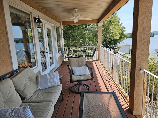 wooden deck with ceiling fan and a water view