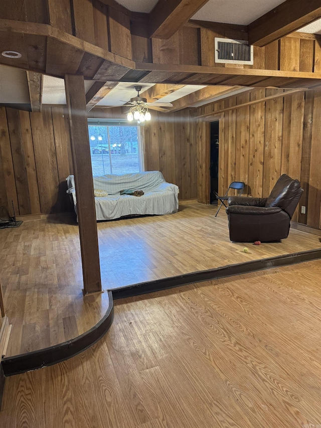 bedroom with beam ceiling, light hardwood / wood-style flooring, and wooden walls