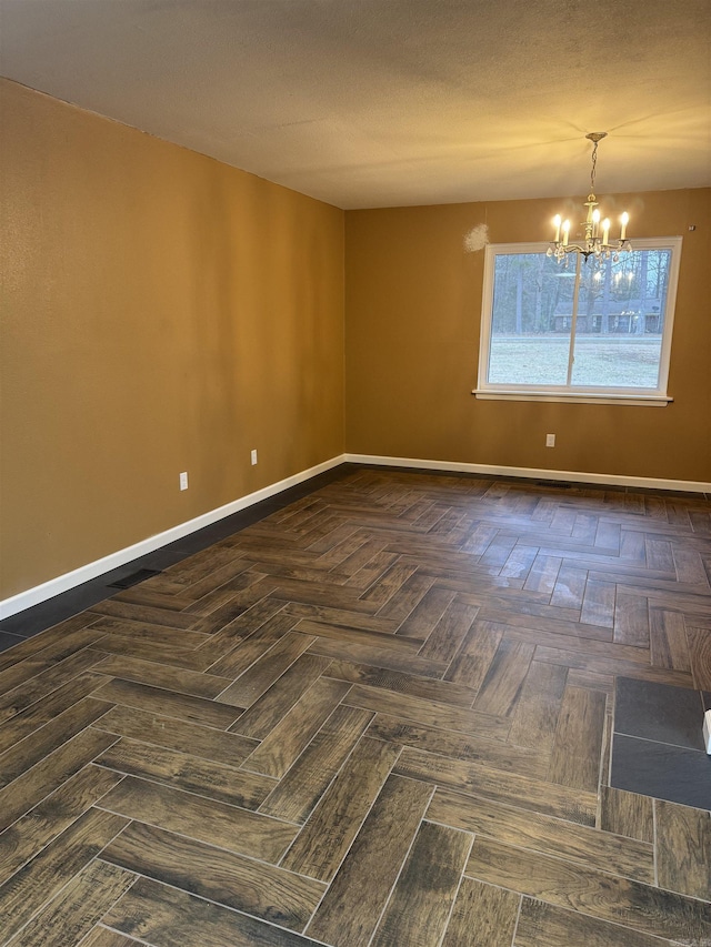 unfurnished room with dark parquet flooring and a notable chandelier