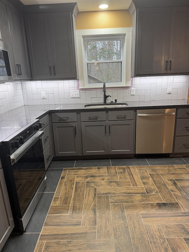 kitchen featuring backsplash, gray cabinetry, sink, and appliances with stainless steel finishes