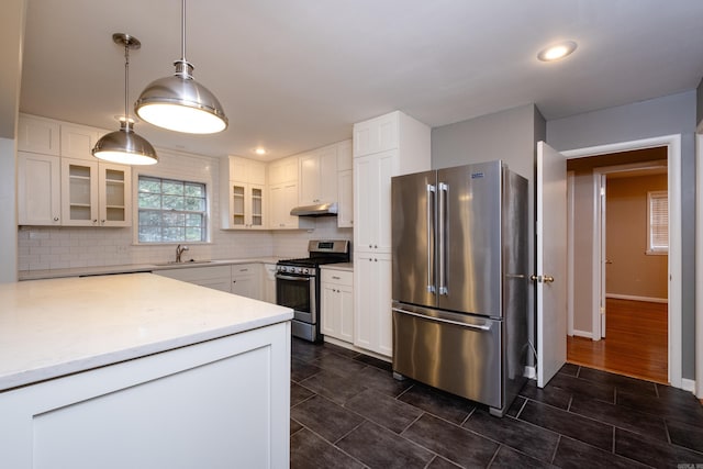 kitchen featuring appliances with stainless steel finishes, tasteful backsplash, sink, decorative light fixtures, and white cabinetry