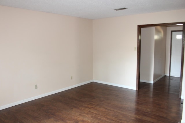 empty room with dark hardwood / wood-style flooring and a textured ceiling