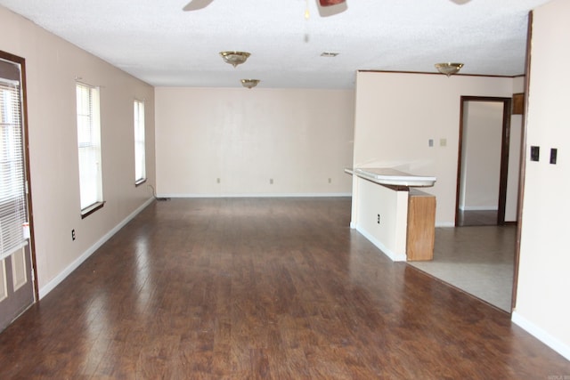 unfurnished room featuring a textured ceiling, ceiling fan, and dark wood-type flooring