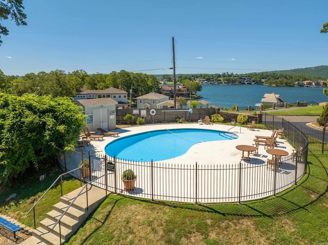 view of swimming pool with a lawn, a patio area, and a water view