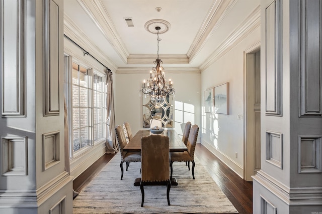 dining space featuring ornamental molding, dark hardwood / wood-style floors, an inviting chandelier, and a tray ceiling